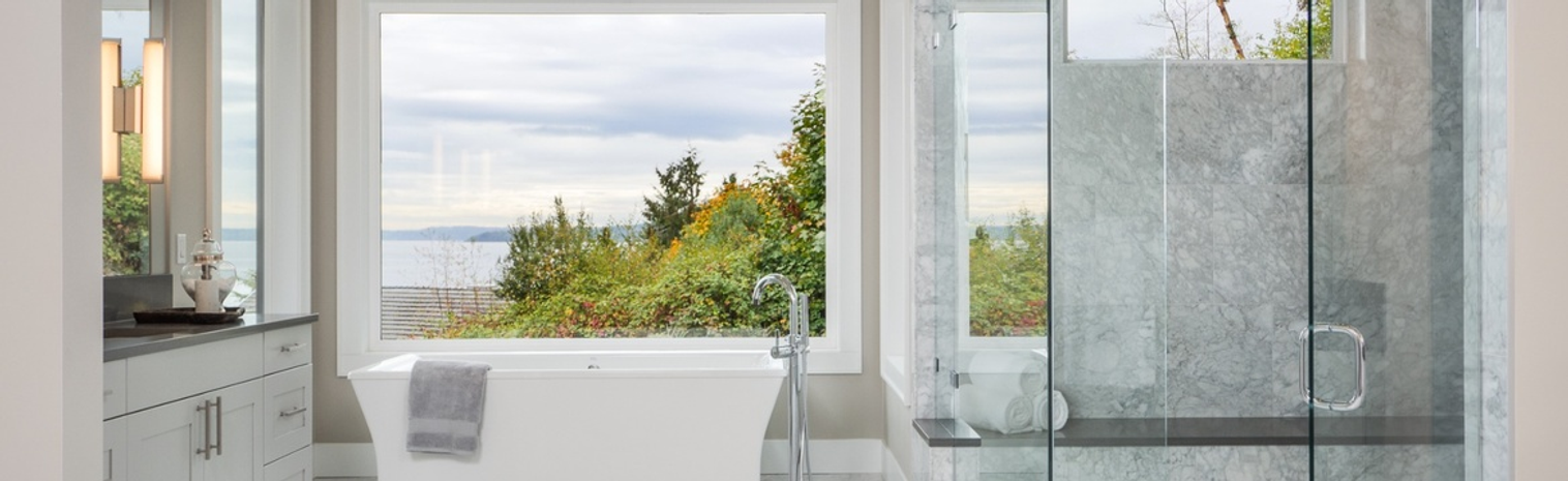 A white bathroom with a corner shower cabin and a colourful view of a lake