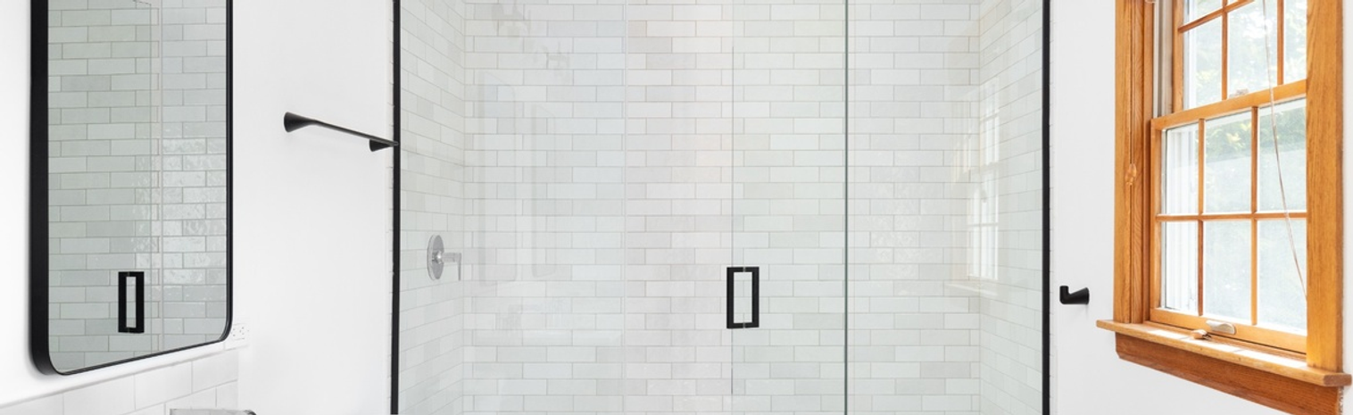 Bathroom with white brick walls, wooden window frames and a niche shower cabin